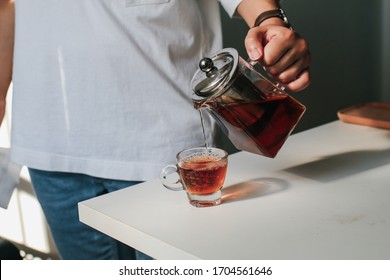 Close up man pouring hot tea from teapot  into small glass near window.Process brewing tea,tea ceremony,Cup of freshly brewed yellow or green herb tea,warm soft light, dark mood.Liquid movement in cup - Powered by Shutterstock