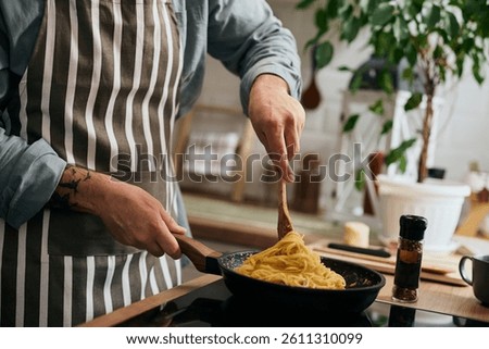 Close up of man preparing spaghetti while cooking in the kitchen.