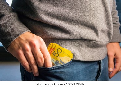 Close up of a man putting Australian Dollar Notes in the pocket 
Australian money banknotes in concept of currency exchange and payment. Money concept. Australian $50 bills 