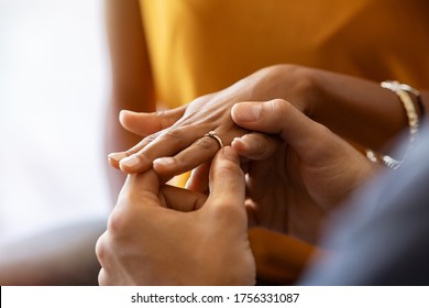Close up of man putting engagement ring on his girlfriend hand. Man is making marriage proposal with golden ring with diamond to his woman. Close up hands of indian guy giving an engagement ring.