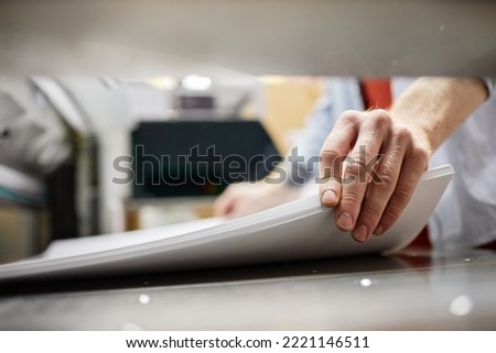 Close up of man putting stack of paper in printing machine at publishing shop, copy space Stock photo © 