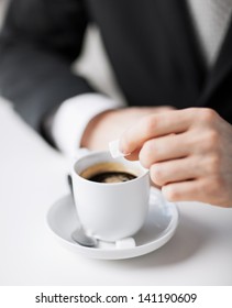 Close Up Of Man Putting Sugar Into Coffee