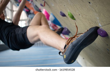Close Up Of Man Rock Climbing At An Indoor Rock Climbing Gym. 
