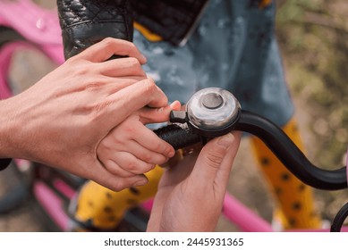 close - up of man 's hand holding bicycle bell with daughter`s hand in the park - Powered by Shutterstock