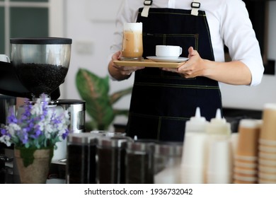 Close up of man serving coffee and tea while standing in coffee shop. Focus on male hands placing a cup of coffee on counter. Concept cafe shop coffee