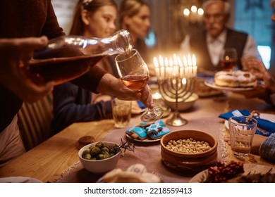 Close Up Of Man Serving Kosher Wine During Hanukkah Family Dinner At Dining Table.