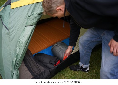 Close Up Of A Man Setting Up A Tent For Camping, Putting Sleeping Bags And Self Inflatable Air Mats Inside The Tent.                   