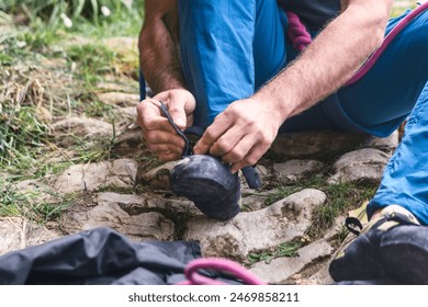 Close up of a man sits on the ground tying his climbing shoes. The scene is casual and relaxed, and the man takes his time getting ready to climb. - Powered by Shutterstock