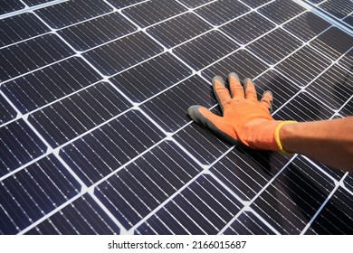 Close Up Of Man Solar Technician Installing Solar Modules For Generating Electricity Through Photovoltaic Effect. Male Hands In Work Gloves Assembling Photovoltaic Solar Panels.