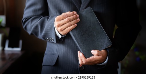 Close Up A Man In A Suit Holding A Bible In Hands