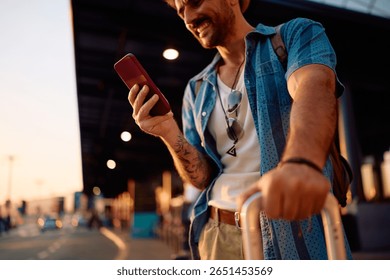 Close up of man with suitcase using mobile phone at the airport. 
