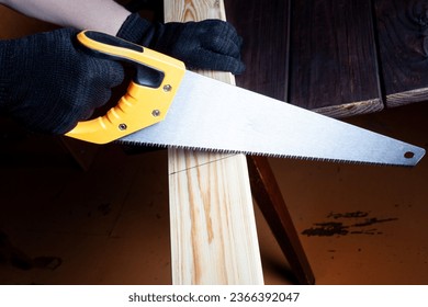 Close up the man use hand saw cutting wood board in the carpenter shop