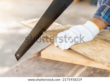 Close up the man use hand saw cutting wood board in the carpenter shop.