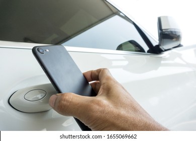 Close up of man uses a smartphone to place near to the door handle of a car for communication to lock, unlock the car.