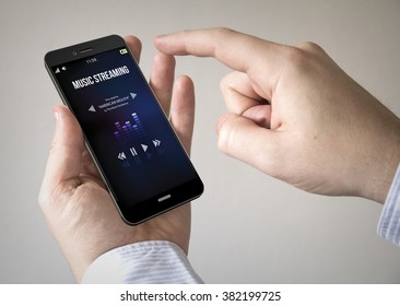Close up of man using 3d generated mobile smart phone with  music streaming app on the screen. Screen graphics are made up.