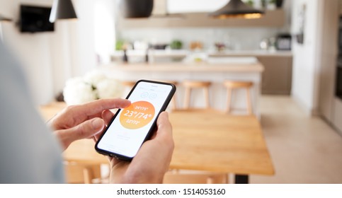 Close Up Of Man Using App On Smart Phone To Control Central Heating Temperature In House