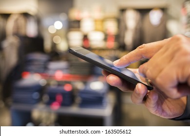 Close Up Of A Man Using Cell Phone In Clothing Store