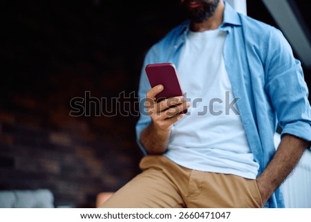 Close up of man using cell phone on front porch. Copy space.