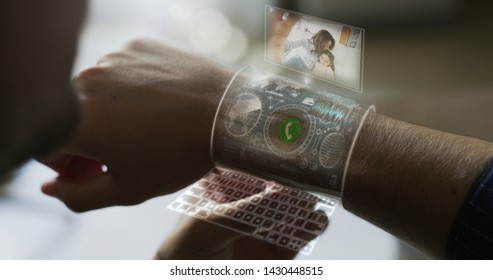 Close Up Of A Man Is Using Futuristic  Armband Liquid Crystals Smart Watch  With The Latest Advanced Augmented Reality Holographic Technology For Call His Wife And Daughter.