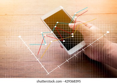Close up of a man using mobile smart phonewith business graph with wooden background.jpg