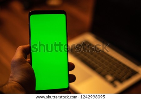 Close up of a man using mobile smart phone indoor, young man using his mobile phone in home with a green screen