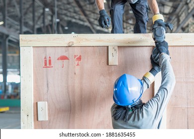 Close up of a man using a pneumatic nail gun to finish the trim wooden box in packing work for storage in warehouse : Is an unsafe working condition
