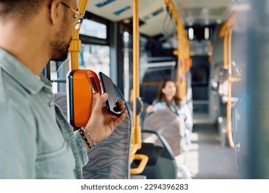 Close up of man using smart phone while paying for a bus fare. 