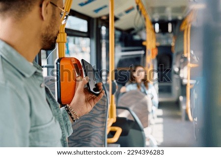 Close up of man using smart phone while paying for a bus fare. 