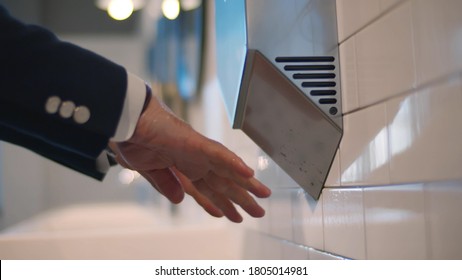 Close Up Of Man Washing Hands And Using Hand Dryer In Modern Public Toilet. Aged Businessman Visiting Office Restroom. Hygiene And Healthcare Concept