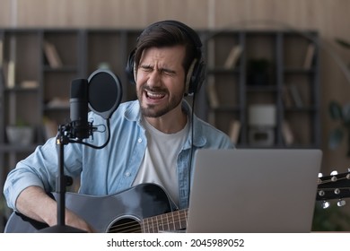 Close Up Man Wearing Headphones Singing In Professional Microphone, Playing Guitar, Musician Artist Recording New Song, Making Music In Home Studio, Using Laptop, Teacher Holding Online Lesson