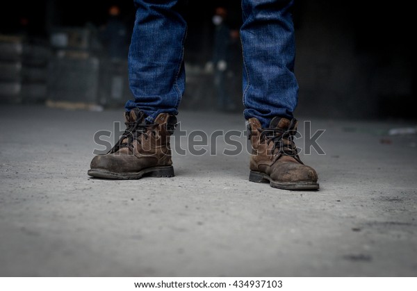 Close up of Man wearing safety shoes brown color
, standing on the street.
