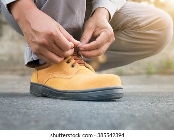 Close Up Of The Man Wears Safety Shoes On Street With Green Light Sun Flare 