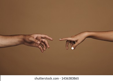 Close Up Of Man And Woman Hand About To Touch With Index Finger. Couple In Love Reaching To One Another In Front Of Brown Background.
