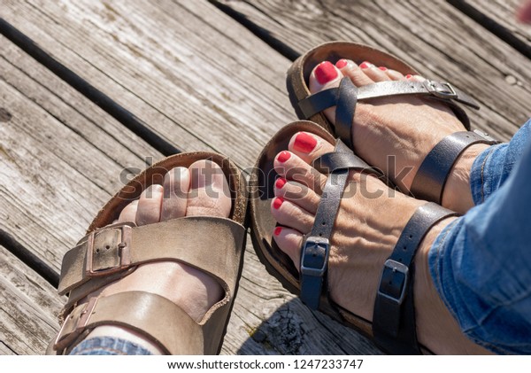 close up of man and woman wearing sandals on\
wood dock in summertime
