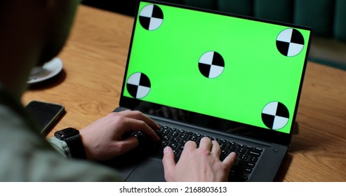 Close Up Of Man Working On Laptop With Green Screen In Coffee Shop.