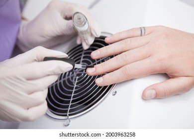 Close Up Of Manicurist Applying Base Coat On Nails Of Client