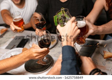 Close up of mans drinking beer and wine in pub. Mans having good time,cheering and drinking cold beer, enjoying friendship together in bar, close up view on hands.