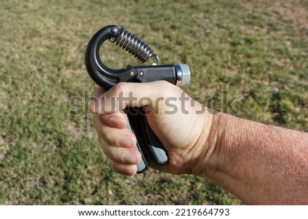 Close up of man's hand using an adjustable hand strengthener to exercise the forearm and strengthen the grip