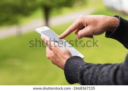 Close up of a man's hand using mobile smart phone outside on sunny summer day