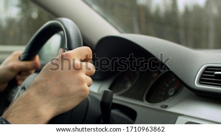 Close up man's hands on the steering wheel of moving car. Driver's point of view, POV. Dashboard