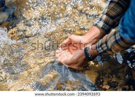Close up of man's hands taking fresh water from a mountain creek. Copy space. 
