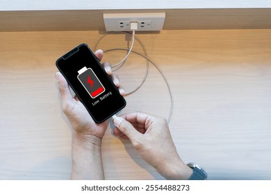 Close up man's hands using smart phone battery low charge battery screen, Businessman holding a smartphone  Low battery warning on a mobile phone. Need to connect the charger to the smartphone icon