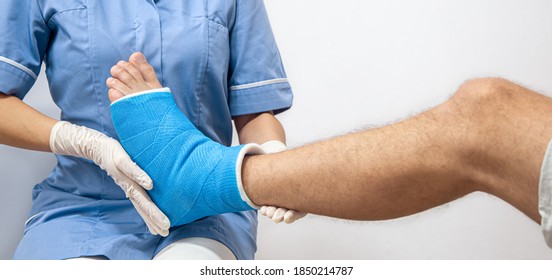 Close Up Of A Man's Leg In A Cast And A Blue Splint After Bandaging In A Hospital.