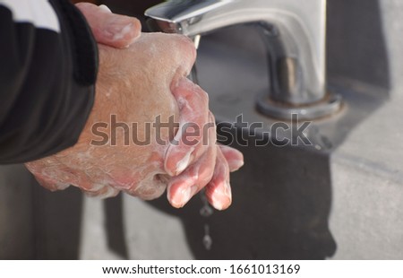 A close up of a man's soapy fingers as he carefully and metoculoulsly washes his hands following advice issued by the World Health Organisation on hand washing to prevent the spread of Coronavirus 