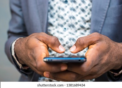 close up of a man's typing on his phone with both hands