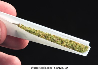 Close up of marijuana joint being rolled on black background