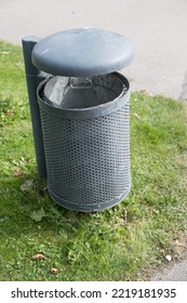 Close Up Of Massive Metal Trash Can Dustbin With Lid Placed On Grassy Surface In Public Park As Concept For Clean Environment And Public Areas