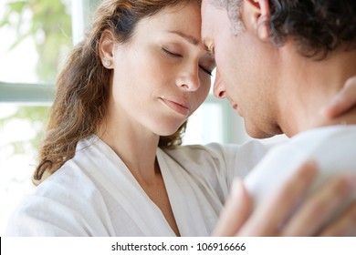 Close Up Of A  Mature Couple Hugging At Home, With Their Heads Together.