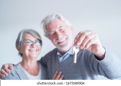 close up of mature man holding a key of a new home or house or some property of both - couple of seniors and pensioners smiling and looking at the key being happy
