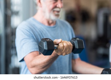 Close Up Of Mature Man Holding Two Dumbbells Doing Exercise At The Gym To Be Healthy And Fitness - Portrait Of Active Senior Lifting Weight